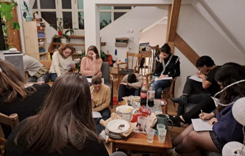 Jeunes priants dans un appartement de Prague avec des assiettes et des verres vides autour.