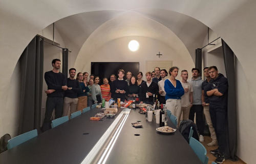 Plein de jeunes debouts autour d'une table dans une salle voutée