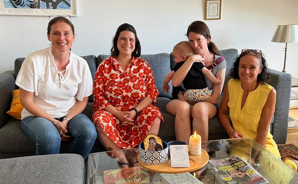 Les mères souriantes sur un canapé. Une tient son bébé dans les bras